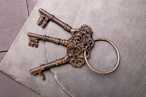 Close-up of a bunch of three old keys on dark plates. Objects on a black background. Concept photo