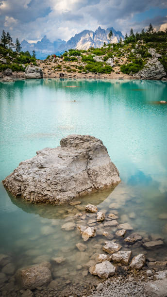 vue sur les rochers atteignant un gros rocher au magnifique lac turquoise sorapis dans l’après-midi. lac sorapis, dolomites, belluno, italie, europe. - mountain rock sun european alps photos et images de collection