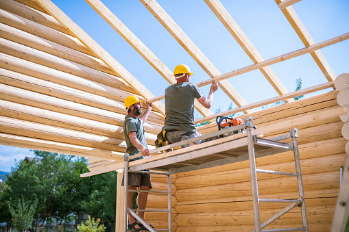 Team of two professional builders working on building a log cabin.