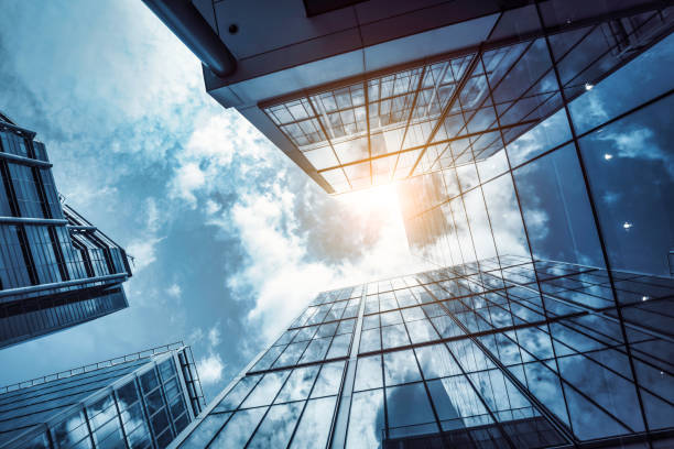 low angle view of a contemporary glass skyscraper reflecting the blue sky - financial building imagens e fotografias de stock