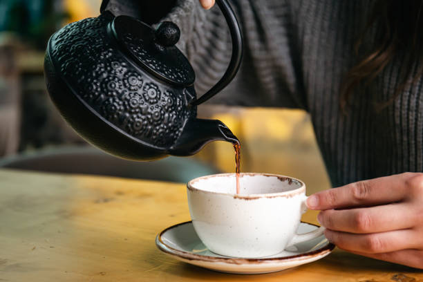 istock Woman in a cafe pour tea from a black cast iron teapot. 1445551056