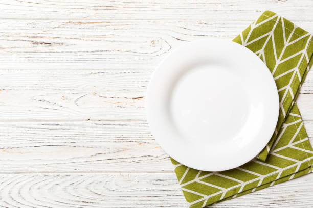 istock Top view on colored background empty round white plate on tablecloth for food. Empty dish on napkin with space for your design 1445551115
