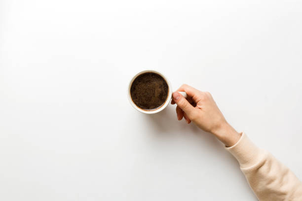 minimalistic style woman hand holding a cup of coffee on colored background. flat lay, top view cappuccino cup. empty place for text, copy space. coffee addiction. top view, flat lay - breakfast cup coffee hot drink imagens e fotografias de stock