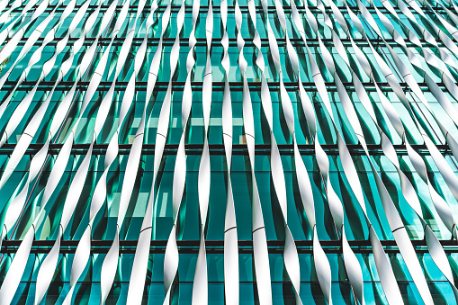 A fragment of the mirrored facade of a building with small square windows. Glazing of the facade with blue glass. Architectural background