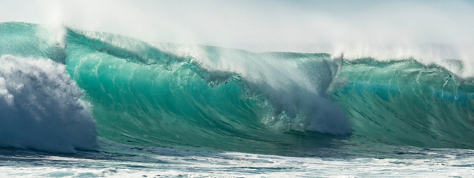 CLOSE UP: Beautiful deep blue tube wave in the wild Pacific Ocean curls towards a remote tropical island on a sunny day in summer. Spectacular shot of wild barrel wave coming from the exotic sea.