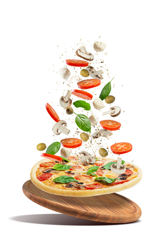 Pizza with mushrooms, tomatoes, cheese and basil on a white background. Falling ingredients. Levitation