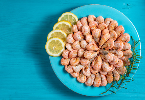 shrimp boiled in a plate with spices on a blue background