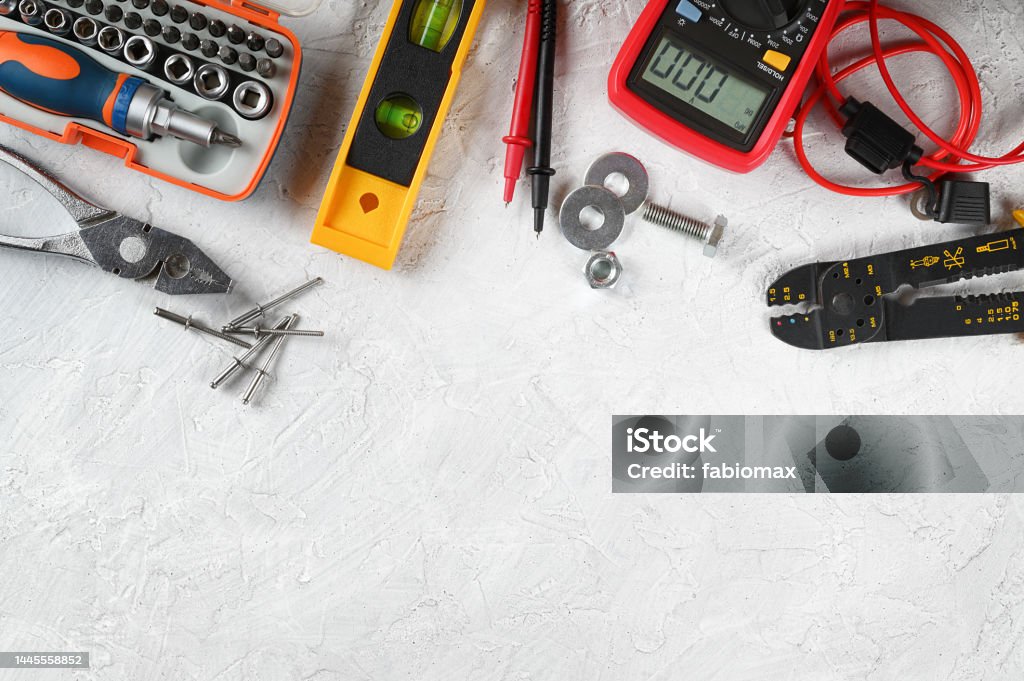 Set of hand tools on white plaster background. Work tools for electrician, carpenter, mechanic, plumber and hobbist. Top view, space for text, flat lay. Commonly used tools for home maintenance work. Electricity Stock Photo