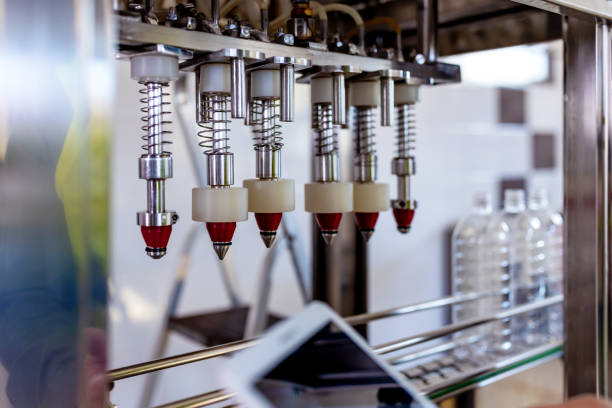 Close up machines filling fresh juice to plastic bottles