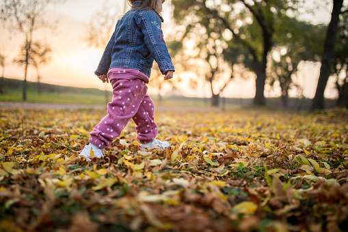 Little cool kid running on autumn leaves.