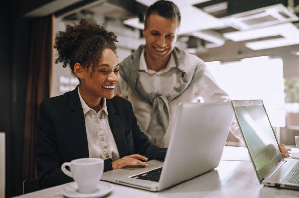 istock Woman sitting man standing joyfully looking at laptop 1445580106