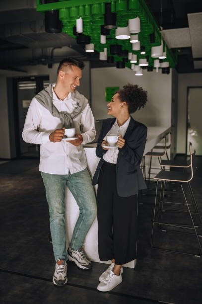 istock Man and woman with coffee standing smiling in office 1445580122