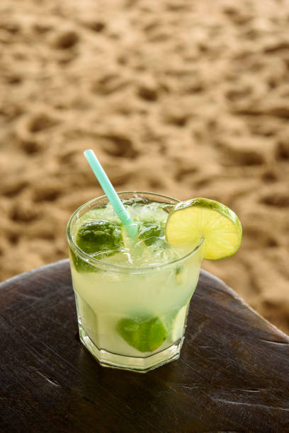 istock Brazilian caipirinha drink on wooden table with sandy beach background. 1445580969