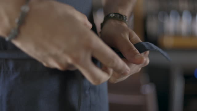 Close-up caucasian hands from side tying blue apron threads cook preparing,Put on cook apron,Zoom up view of professional chef tying an apron around his waist