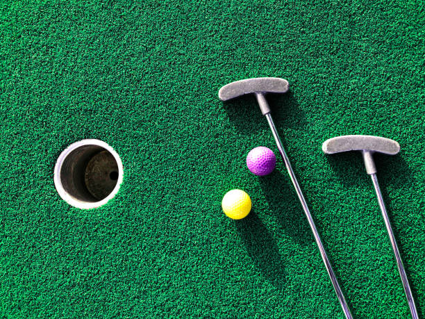 mini golf clubs and balls on putting green - putten stockfoto's en -beelden