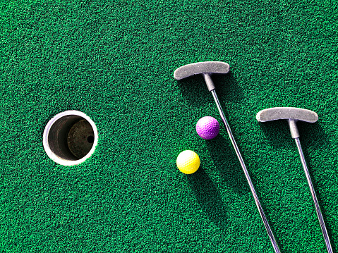 Mini golf clubs and balls on putting green background