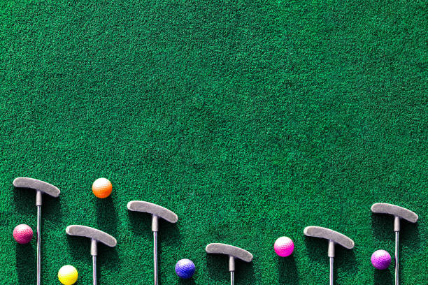 Multiple mini golf clubs and balls on putting green background with copy space