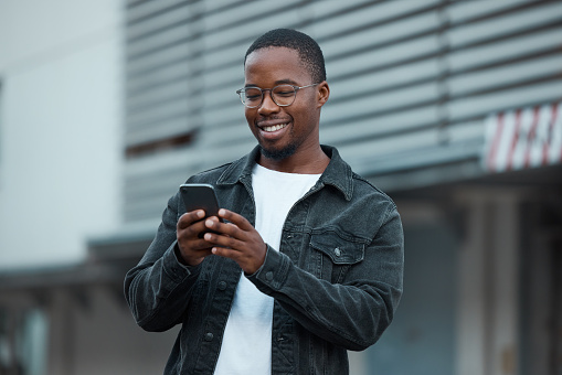 Black man, phone and social media in city reading text message or communication on social network app. African American person, chat conversation and happy on 5g mobile smartphone in Atlanta smile