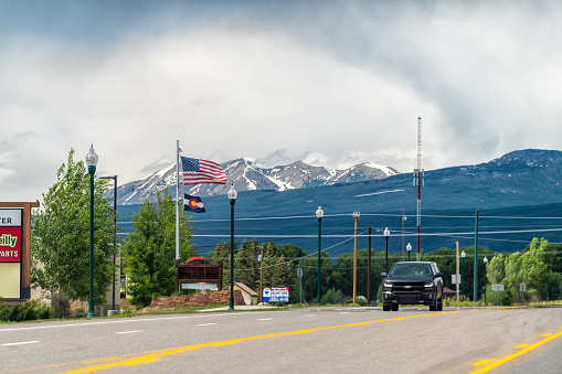 Gunnison, USA - June 20, 2019: Highway 50 road with traffic cars in small city, mountains town and mount Crested Butte of Rocky mountains in background