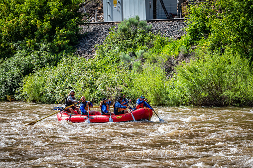 Glenwood Springs, USA - June 29, 2019: Group of candid people on boat in Colorado's Roaring Fork River white water rafting in summer season
