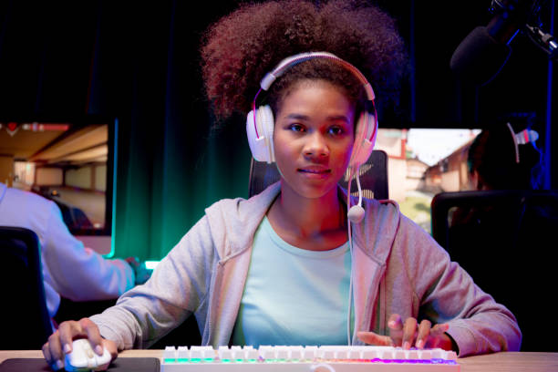 Young African American woman wearing headset play video game and live streaming online with microphone at home, gaming and esport for competition or casting game, broadcast and entertainment concept. stock photo