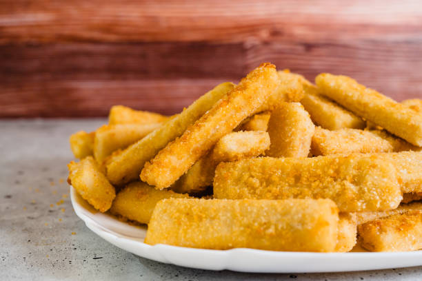 istock Fish sticks in a crunchy golden breading close-up on white plate on the kitchen table 1445608309