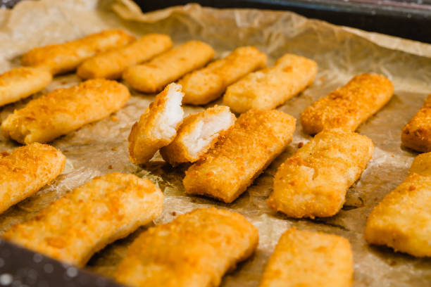 istock Crunchy breaded fish sticks made from wild caught Alaskan Pollock close-up on a baking pan 1445608311
