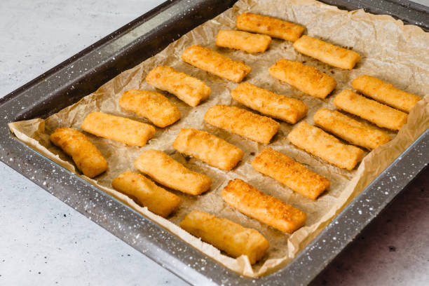 istock Baking pan with fish sticks close up. Crunchy delicious lightly breaded with panko bread crumbs fish sticks 1445608378