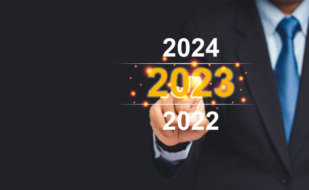 istock Businessman in a suit pointing to a digital 2023 calendar on virtual screen while standing on a black background 1445615574