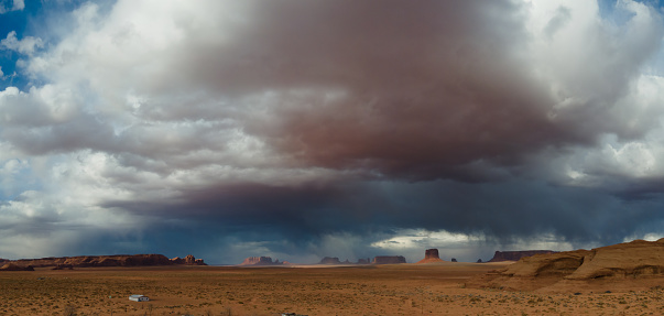 Panorama Monument Valley Desert Rock Formations Under a Dramatic Springtime Sky at Dusk, Rainy Cloudscape over Rocky Arid Terrain in Navajo Country at the Border of Arizona and Utah