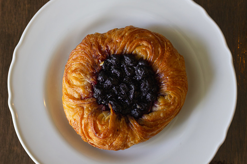 Blueberry roll croissant on white plate. Bakery sweet pastry item dessert from top