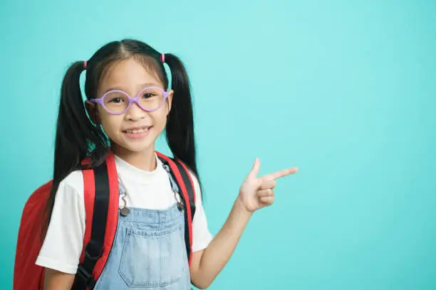 Photo of Close-up kid schoolgirl Pointing Fingers At Copy Space.