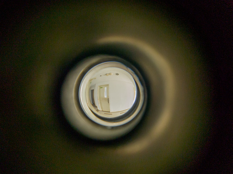 Close up eye peep hole on hotel wood door looking to outside the room.