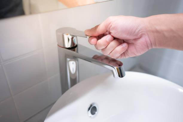 バスルームの水道の蛇口を閉じる男性の手 - water saving ストックフォトと画像