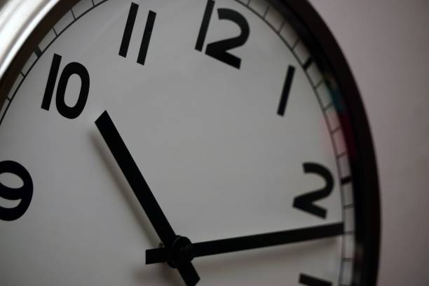 istock Closeup shot of a wall clock with a white base and black dials 1445642858