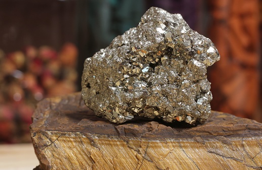 Pyrite Specimen on Raw Tigers Eye Rock With Dried Herbs in Background Shallow DOF