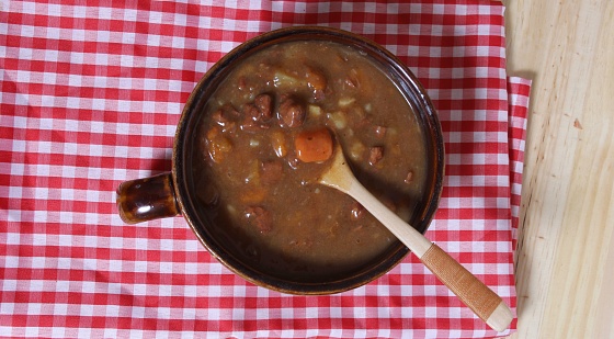 Bowl of Beef Stew with Wooden Spoon on Red and White Checkered Cloth