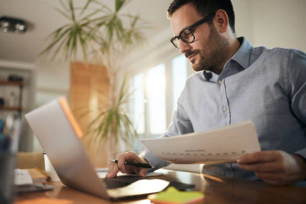 istock Male entrepreneur working on laptop and reports at home office. 1445647042