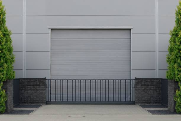 istock Gate or roller shutter with application to factory, warehouse or hangar. Outside, trees on the sides 1445649737