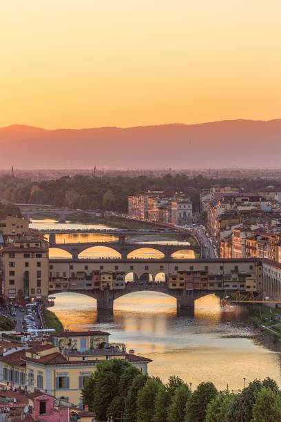 vertical shot of the ponte vecchio bridge at the river arno in florence at sunset - ponte vecchio imagens e fotografias de stock