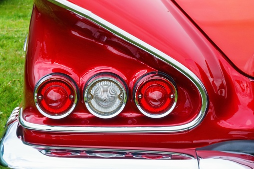 A closeup of tail lights and a wing of the vintage red american car