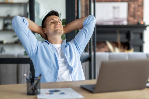 istock Dreaming about good future and visualizing, new opportunities. Satisfied young male businessman resting at workplace in the office, put his hands behind his head 1445650455