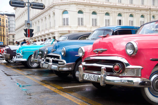 La habanal, Cuba. 05/14/2018: American classic cars driving through the streets of la habana in cuba in which you can see its colonial architecture in contrast with the colorful vehicles.