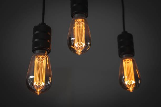 istock Closeup of small light bulbs hanging in a dark room 1445651473