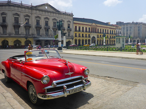 La habanal, Cuba. 05/14/2018: American classic cars driving through the streets of la habana in cuba in which you can see its colonial architecture in contrast with the colorful vehicles.