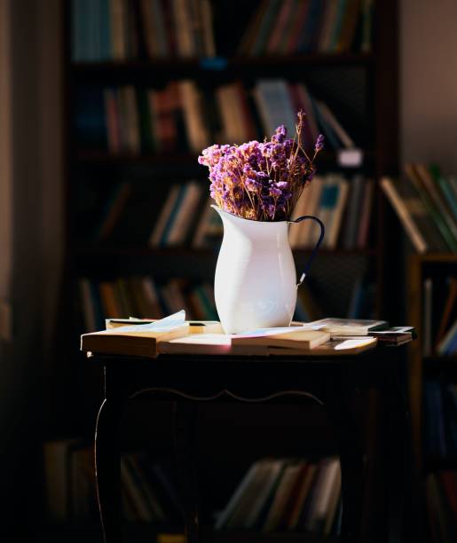 istock White vase with purple flowers alongside books on a table 1445654659