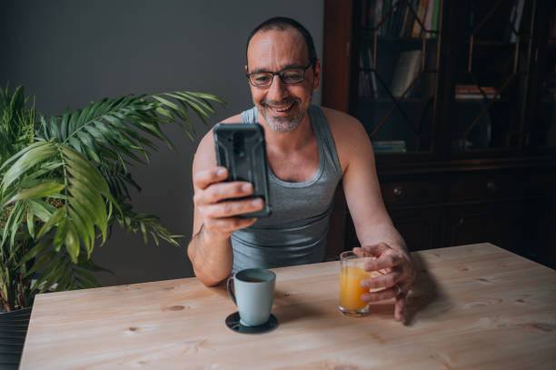 istock Mature man sitting in the kitchen and using smartphone 1445656473