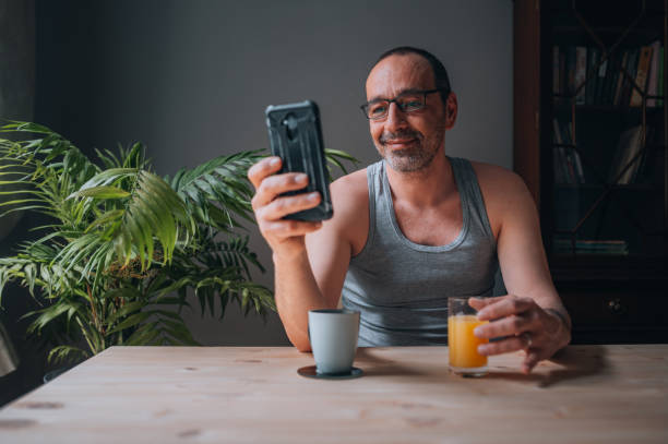 istock Mature man sitting in the kitchen and using smartphone 1445656484