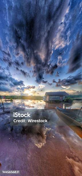 Vertical Panoramic View Of Small House On The Lakeshore Against Dark Sunset Clouds Stock Photo - Download Image Now