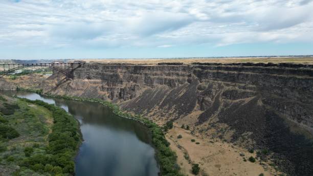 istock Small river with a bridge over it and a cliff under a blue cloudy sky 1445657475
